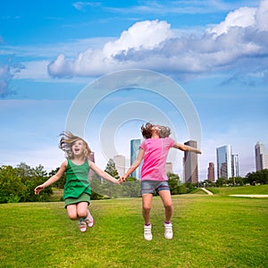 Two girls friends jumping happy holding hand in city skyline