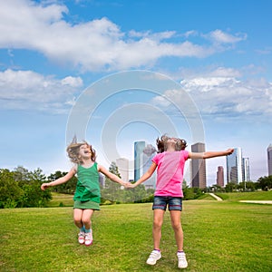 Two girls friends jumping happy holding hand in city skyline