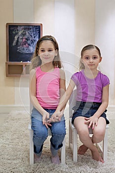 Two girls in the gameroom sit on chairs