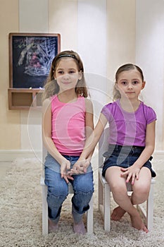 Two girls in the gameroom sit on chairs photo