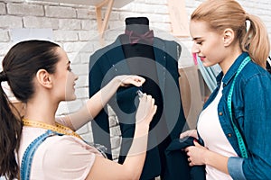 Two girls at garment factory desining new man suit jacket.