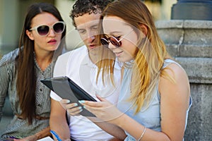 Two girls and the guy with interest look at the tablet screen.