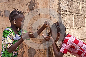 Two Girls Happily Sharing Water from tap in Bamako, Mali