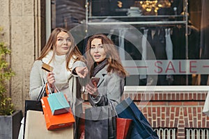 Two girls are happy with a credit card in front of showwindow wi