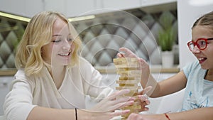 Two girls have fun playing Jenga together - board game to remove wooden blocks and kids leisure concept