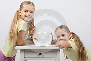 Two girls have a small fishbowl with goldfish