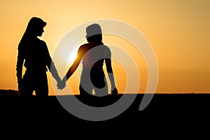 Two girls holding each other hands. Ladies couple on the beach.