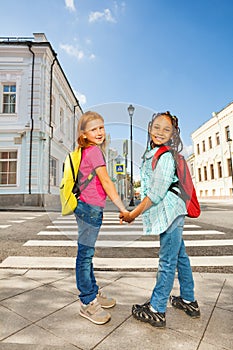 Two girls holding hands and standing near road