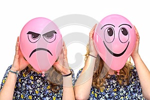 Two girls holding pink balloons with facial expressions