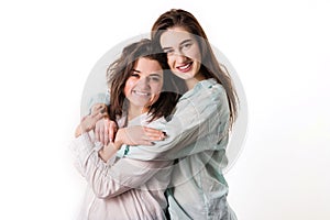 Two young girls hug on a white background.