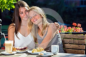 Two girls hugging in outdoor cafe