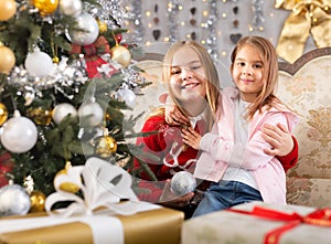 Two girls hugging on sofa in Christmas interior