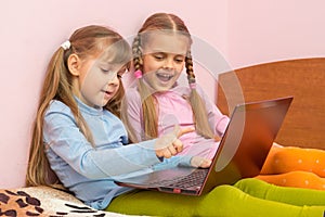 Two girls include laptop at work, sitting on bed