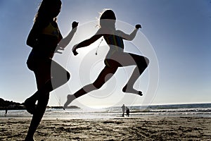 Two girls jumping on the beach