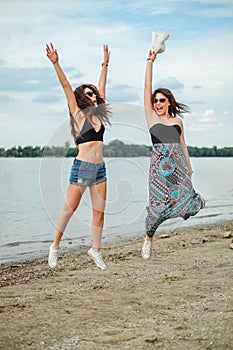 Two girls jumping by the water