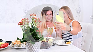 Two girls laughing girls talking on video communication on smartphone at home, selective focus