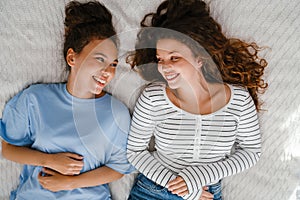 Two girls laughing while lying in bed together