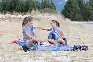 Two girls laughing out loud on the mountain while having a snack