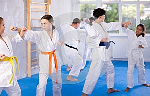 Two girls learn to throw punches and kicks in sparring for karate training in gym