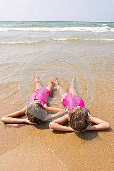 Two girls lie on your back on the sandy beach halfway in the wate