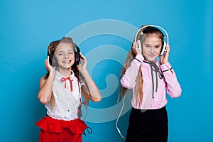 Two girls are listening to music with headphones and dance