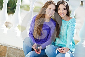 Two girls listening to music on their smartphones.