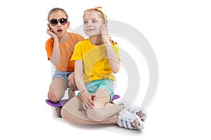 Two girls listenning to the music and sitting on skateboard over white