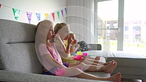 Two girls and little boy children watching tv. Kids eat popcorn and drink juice