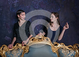Two girls look at each other. Haughty eyes. A scene from the film. Girls from high society. Shooting in studio. Stage image. Inter photo