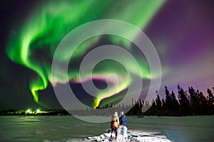 Two girls look northern lights, which stretches beyond horizon
