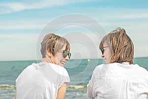 Two girls looking at each other by the sea. Expression of friendship and complicity