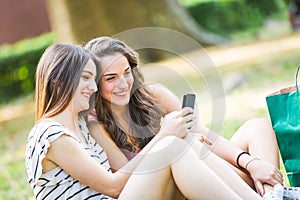 Two girls looking at smart phone at park
