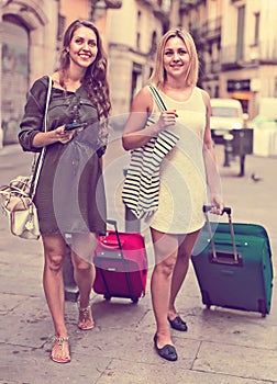 Two girls with luggage at street