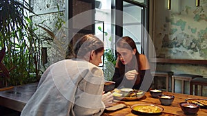 Two girls at lunch, they sit and talk to each other wispering