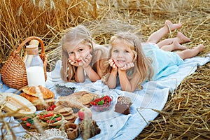 Two girls are lying on a blanket in a wheat field. Sisters on the background of rye ears. Picnic with a wooden board and a blanket