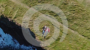 Two girls lying in the grass at the cliffs of the Irish coast - drone view from above