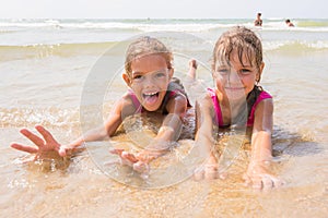 Two girls lying in shallow water and a fun look into the frame