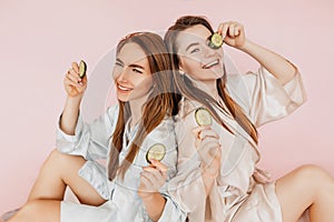 Two girls make homemade face beauty masks. Cucumbers for the freshness of the skin around the eyes. Women take care of youthful