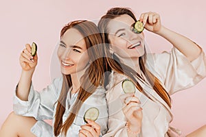 Two girls make homemade face beauty masks. Cucumbers for the freshness of the skin around the eyes. Women take care of youthful