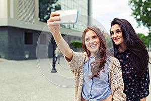 Two girls making funny selfie on the street, having fun together