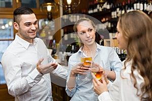 Two girls with man at bar