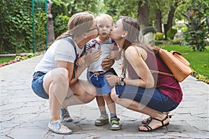 Two girls mom kiss their capricious little boy child in the park. Not a traditional family