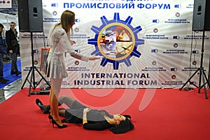 Two girls, one lying on the floor, making selfie at the red carped zone during public event.