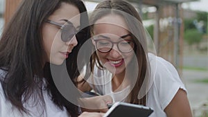 Two girls in the open air read an e-book