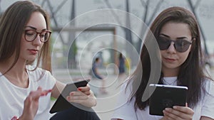 Two girls in the open air read an e-book