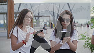 Two girls in the open air read an e-book