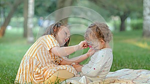 Two girls paint each other's faces at a picnic in the park