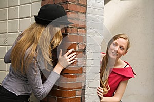 Two girls peeking around the wall