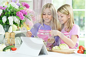 Two girls in pink aprons preparing fresh salad