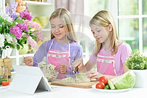 Two girls in pink aprons preparing salad